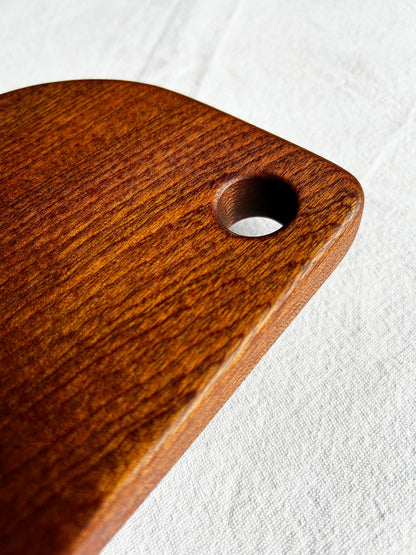 Wooden cutting board with a hole for hanging on a white background