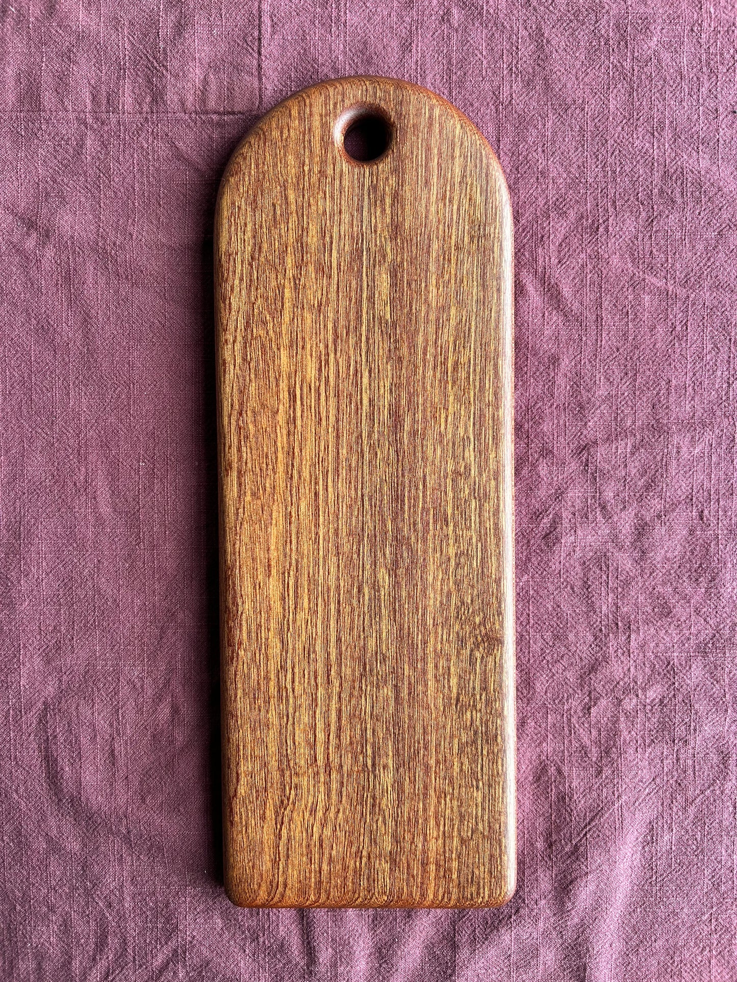 Sapele wood serving board on a textured purple fabric background