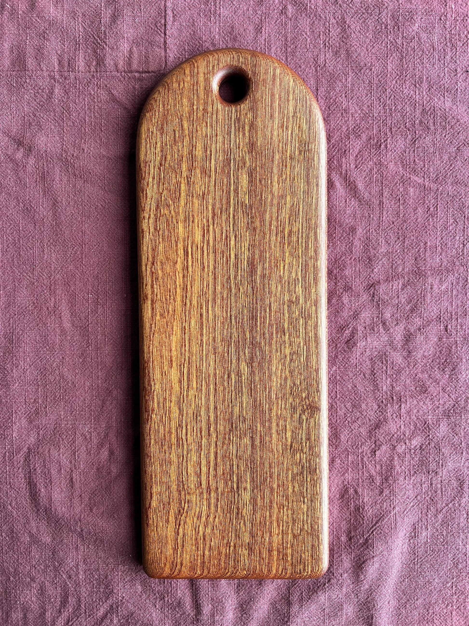 Sapele wood serving board on a textured purple fabric background