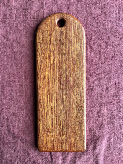 Sapele wood serving board on a textured purple fabric background
