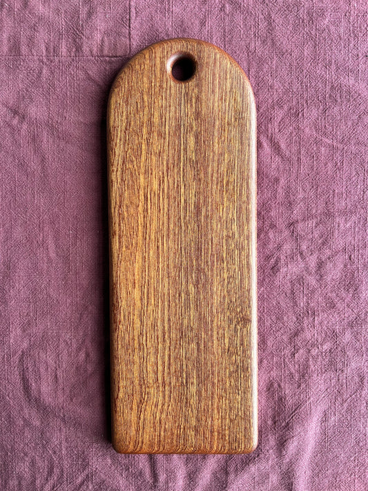 Sapele wood serving board on a textured purple fabric background