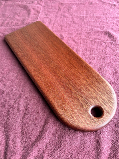 Wooden charcuterie board with a hole on a purple fabric background
