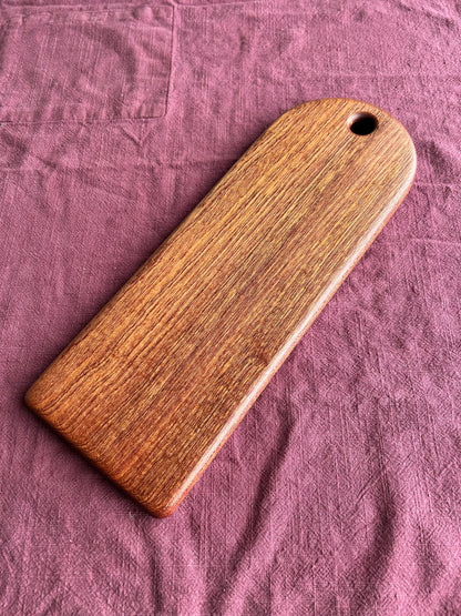 Chocolate brown wood food serving paddle on a purple fabric background